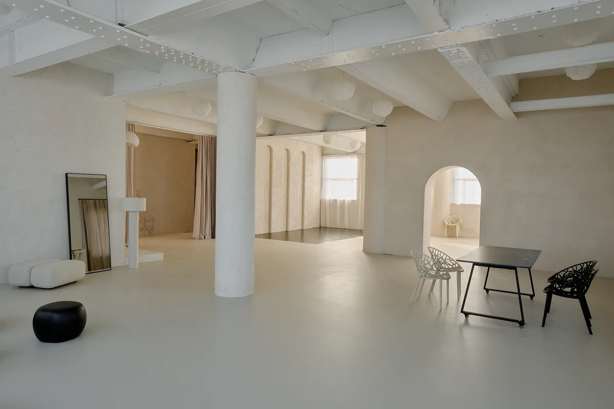 Gaia Studio — warmer Raumüberblick mit Säule, Esstisch und Rundbögen